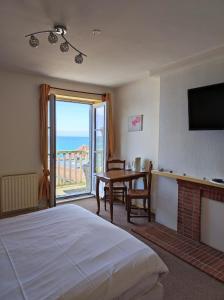 a bedroom with a bed and a table and a television at Les Galets Bleus in &Eacute;tretat