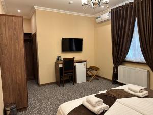 a hotel room with two beds and a desk and a television at Rayyan Hotel Samarkand in Samarkand