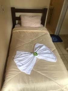 uma gravata borboleta branca numa cama branca em Pousada Estação Lunar em São Domingos