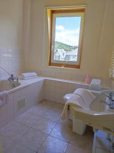 baño con bañera, lavabo y ventana en Les Galets Bleus, en Étretat