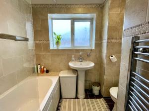 uma casa de banho com um lavatório e uma banheira ao lado de um lavatório em Double Room in Cosy Quiet Home - House Shared with One Professional em Bristol