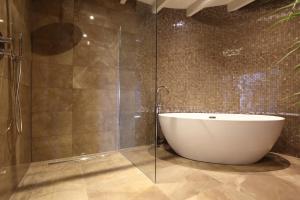 een badkamer met een bad en een glazen douche bij Hoogheem Erfgoed & Logies in Nieuwolda