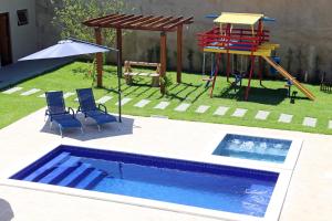 a pool with two chairs and a playground with a slide at Pousada das Bandeiras in Olímpia