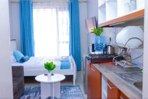 a small room with a bed and a kitchen with a sink at LaMeg2 Furnished Studio with Pool - Kiambu Rd in Nairobi