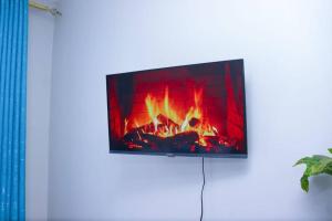 a flat screen tv hanging on a wall with a fireplace at LaMeg2 Furnished Studio with Pool - Kiambu Rd in Nairobi