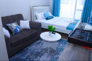 a living room with a couch and a bed and a table at LaMeg2 Furnished Studio with Pool - Kiambu Rd in Nairobi
