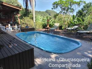 a pool in a backyard with chairs and a table at Suíte Vista Mar Praia Estaleiro Balneário Camboriú in Balneário Camboriú