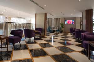 a lobby with a checkered floor and purple chairs at Aris Star in Tabuk
