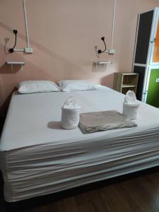 Una cama con toallas y sombreros encima. en Urban Hostel Bangkok, en Bangkok