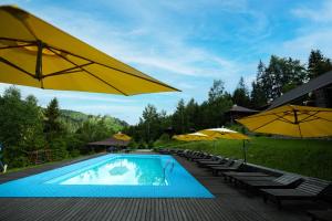 a swimming pool with yellow umbrellas and chairs at Медовий двір in Rozhanka Nizhnyaya