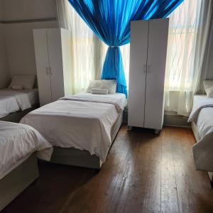 1 dormitorio con 2 camas y cortina azul en Msunduzi River View backpackers, en Pietermaritzburg