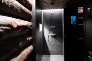 a bathroom with a walk in shower next to a wooden wall at Villa Lake Ruka in Ruka