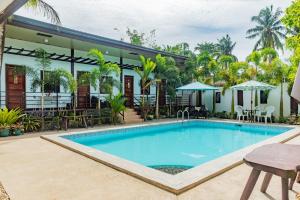 a pool at a resort with tables and chairs at Teteng's Apartelle in San Vicente