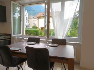 einen Esstisch mit Stühlen und ein großes Fenster in der Unterkunft Henry's Apartments Interlaken in Interlaken