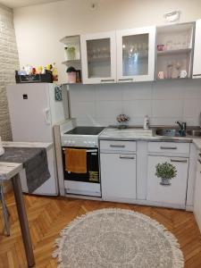 a kitchen with white appliances and a table and a rug at Rákóczi Guesthouse Miskolc in Miskolc