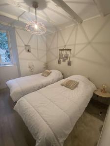 two beds in a white room with a chandelier at Maison de campagne in Paulinet
