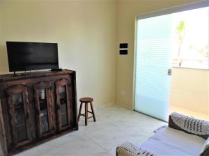 a living room with a flat screen tv on a wooden cabinet at Apto Aluguel na Temporada Pé na Areia Peruíbe SP in Peruíbe