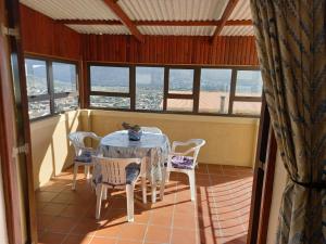 een tafel en stoelen in een kamer met ramen bij A Place in Thyme in Fish hoek