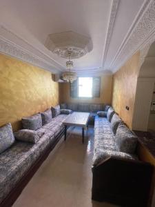 a living room with a long couch and a table at Fully equipped ground floor apartment in Safi