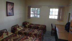 a room with two beds and a desk and two windows at Camp Jonathan in Sodwana Bay