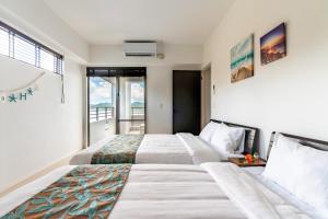 1 Schlafzimmer mit 2 Betten und einem Balkon in der Unterkunft Lala court seaside Yagaji / Vacation STAY 3226 in Nago