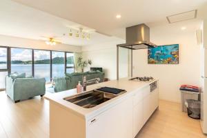 eine Küche mit einem Waschbecken und ein Wohnzimmer in der Unterkunft Lala court seaside Yagaji / Vacation STAY 3226 in Nago