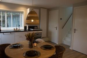 a kitchen with a table with chairs and a dining room at Vakantiehuis 't Hertenkamp in Ouddorp