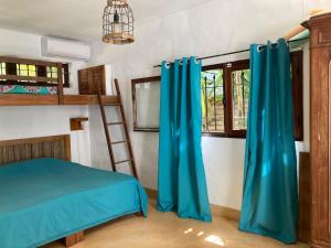 a bedroom with a bed and a ladder and blue curtains at BlueMoon Villa on The Beach in Trou dʼ Eau Douce