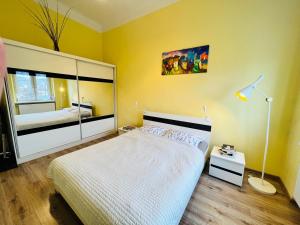 - une chambre avec un lit blanc et un mur jaune dans l'établissement Wolności 21 Jelenia Góra, à Jelenia Góra