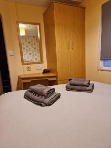 two towels sitting on top of a bed in a room at Family or couple 3-bed cosy home with fireplace, 50 deposit required, self-catering in Hastings