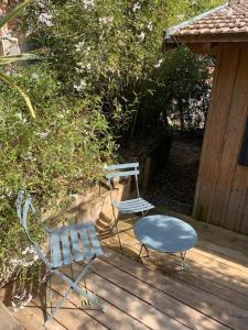2 chaises et une table sur une terrasse en bois dans l'établissement Cabane Chic au Cap Ferret, à Lège-Cap-Ferret