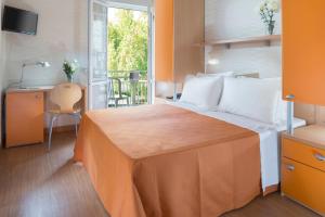 a bedroom with a bed and a desk and a window at Hotel Sampaoli in Bellaria-Igea Marina