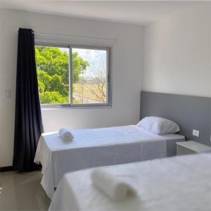 1 dormitorio con 2 camas y ventana en Victoria Apart & Suites, en Encarnación
