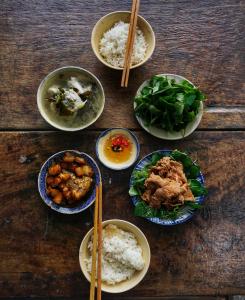 een houten tafel met kommen eten en eetstokjes bij nhà Ba cơm Má in Phương Phi