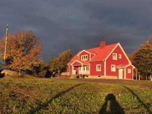Sollebrunn的住宿－Äppelgården，站在红房子前面的人的影子