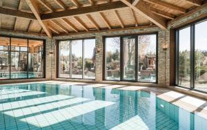 een binnenzwembad met glazen ramen en een groot zwembad bij Parkhotel am Soier See in Bayersoien