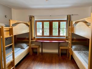 a room with bunk beds with a table and a window at BLSV Sportcamp direkt im Wandergebiet Spitzingsee in Schliersee