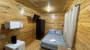 um pequeno quarto com uma cama num quarto com paredes de madeira em Lindos e novos Chalés na região central de Foz em Foz do Iguaçu