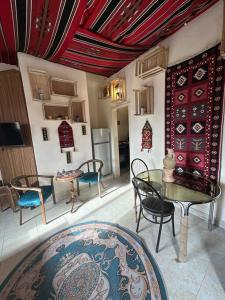 Una sala de estar con mesas y sillas y una cocina. en Antica old apartment al-lwebdeh, en Amán