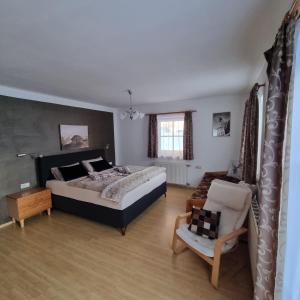 een slaapkamer met een bed en een stoel erin bij Haus Manuela sonnige Aussicht mit Bergpanorama inkl NATIONALPARK CARD in Rauris