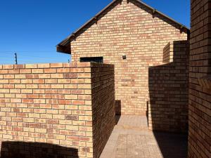 a brick wall next to a brick building at Zen Stone Guest House in Postmasburg