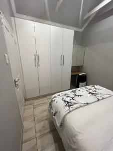 a bedroom with a bed and white cabinets at Zen Stone Guest House in Postmasburg
