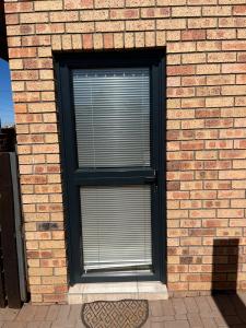 a window with blinds in a brick wall at Zen Stone Guest House in Postmasburg +3 photos