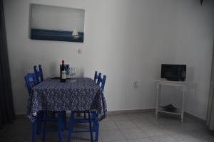 uma sala de jantar com uma mesa com cadeiras azuis e uma televisão em Relaxing and Comfortable Studio Near Falasarna Beaches em Plátanos