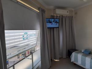 Zimmer mit einem Fenster und einem TV an der Wand in der Unterkunft Departamento Peatonal in Paraná