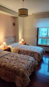 um quarto de hotel com duas camas e uma janela em O Fogar em Moaña