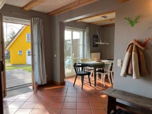 a dining room with a table and a yellow house at Ferien direkt am Wasser mit Hund in Krakow am See