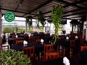 um restaurante com mesas pretas e cadeiras e plantas de madeira em Hotel Valle Escondido em Rosario de Lerma