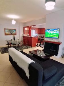 a living room with a couch and a flat screen tv at Thira Apartment near Athens Airport in Spata
