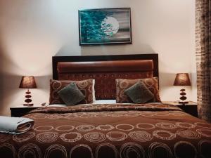 a bedroom with a brown bed with two lamps at Seaview Lodge Guest House in Karachi